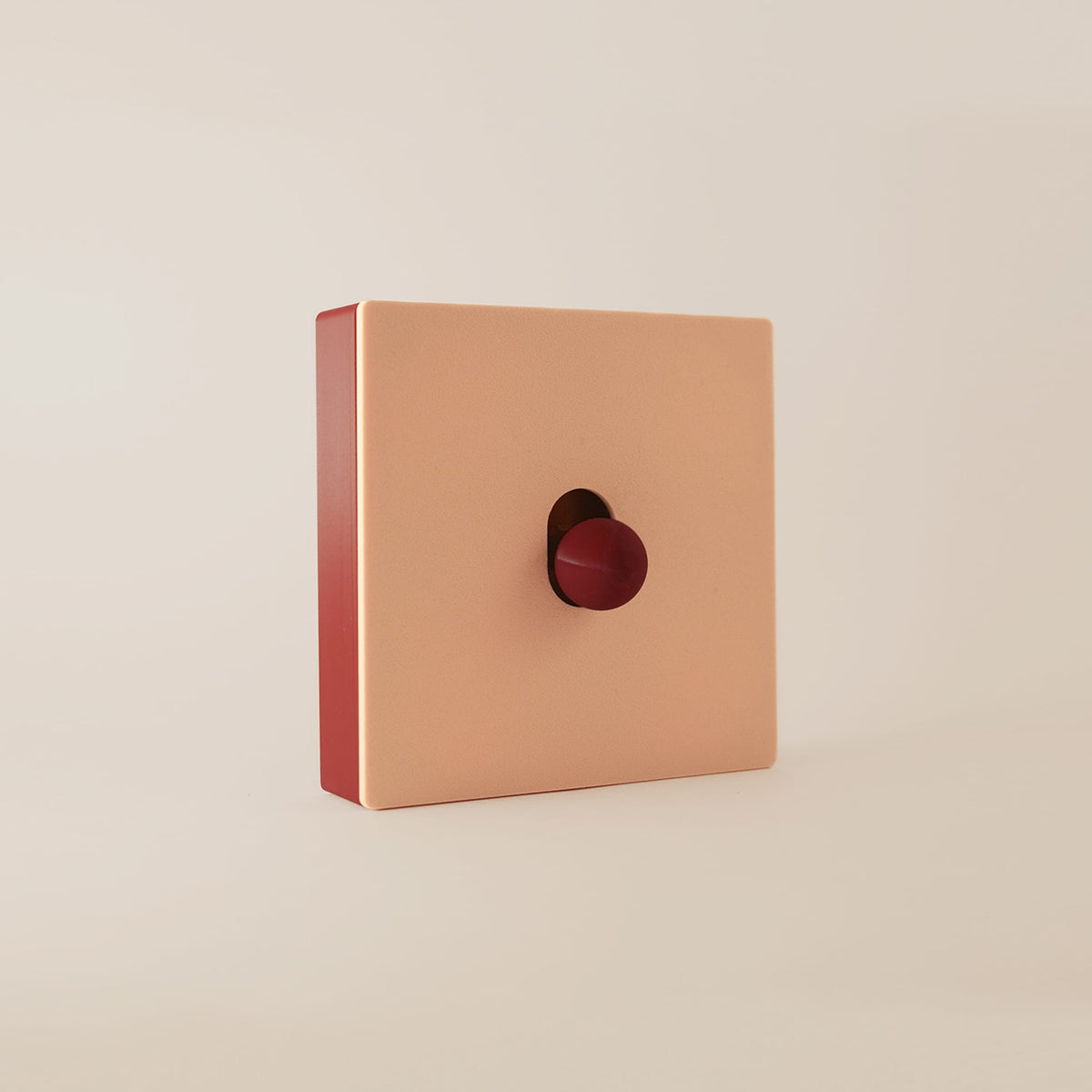 Cache interrupteur Melba modulable, façade beige aimantée sur cadre rouge érable, vue de trois-quarts